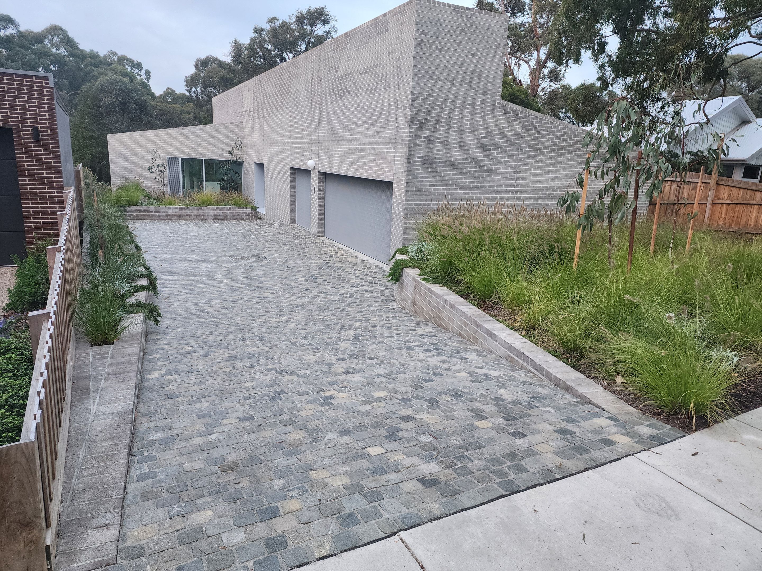 Two-storey brick house with a sloped driveway and garage doors