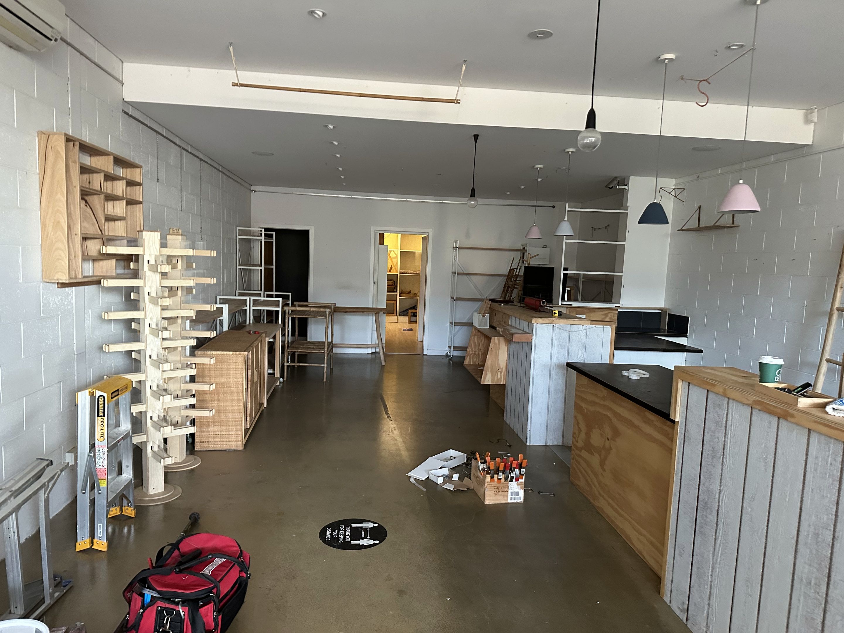 Empty retail space mid-fitout with pendant lights and plywood counters