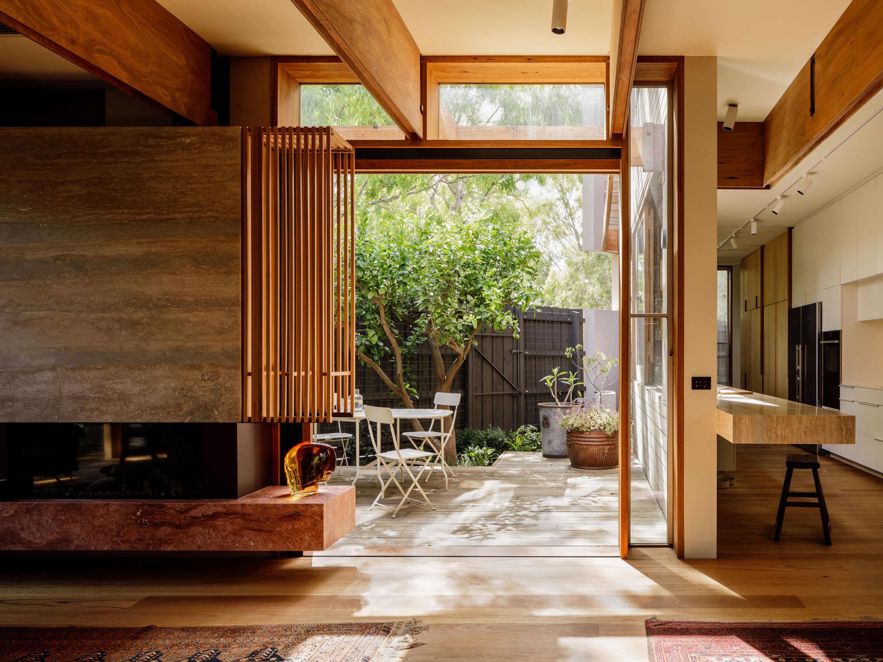 Fireplace with a stone hearth opening onto a rear deck and courtyard