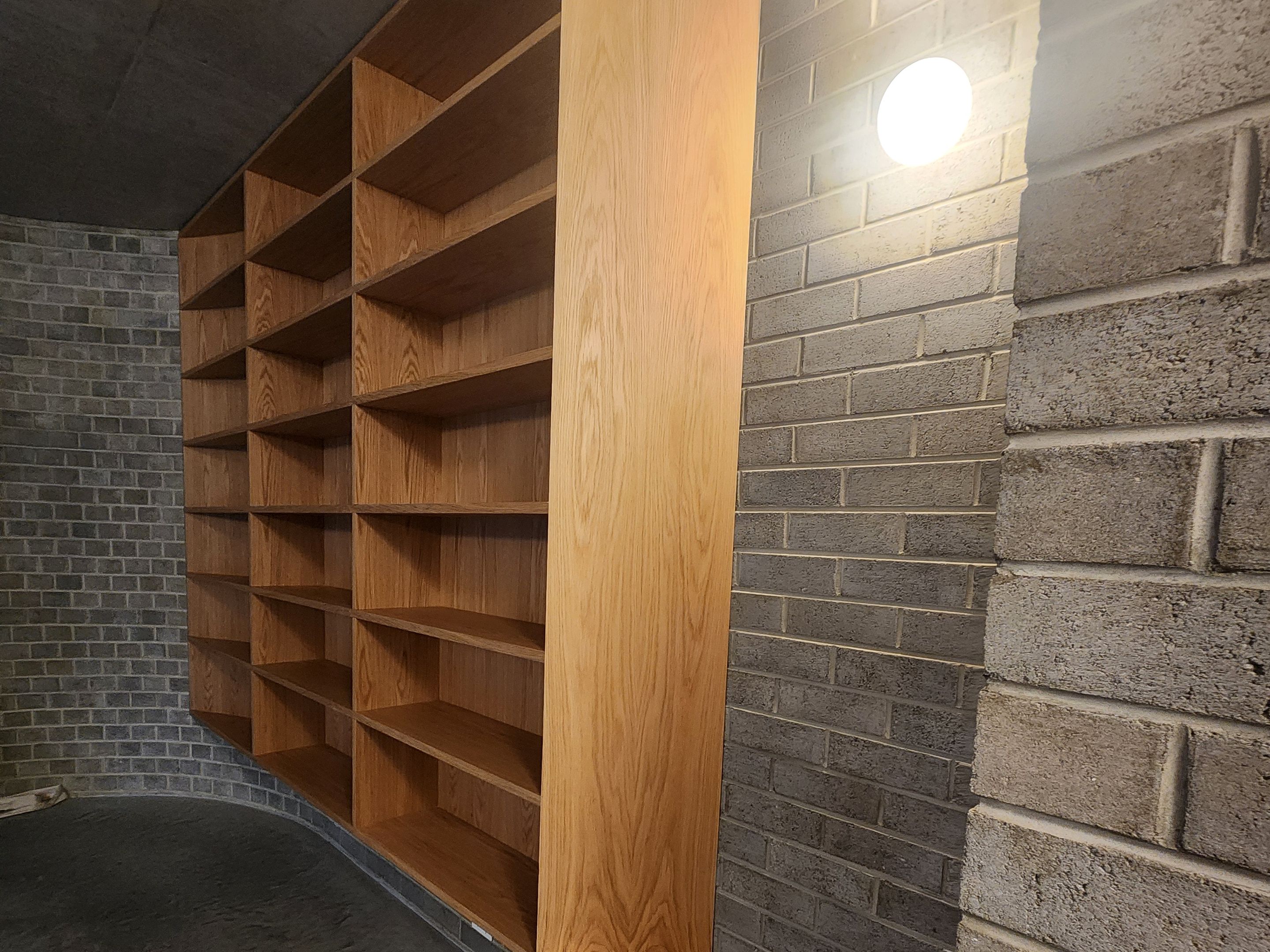 Curved built-in shelving beside a brick wall and pendant light