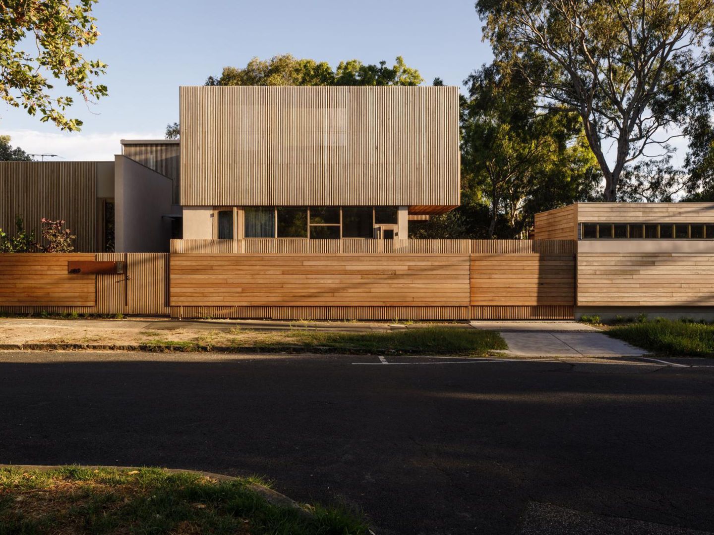 Timber-clad two-storey house behind a slatted timber front fence