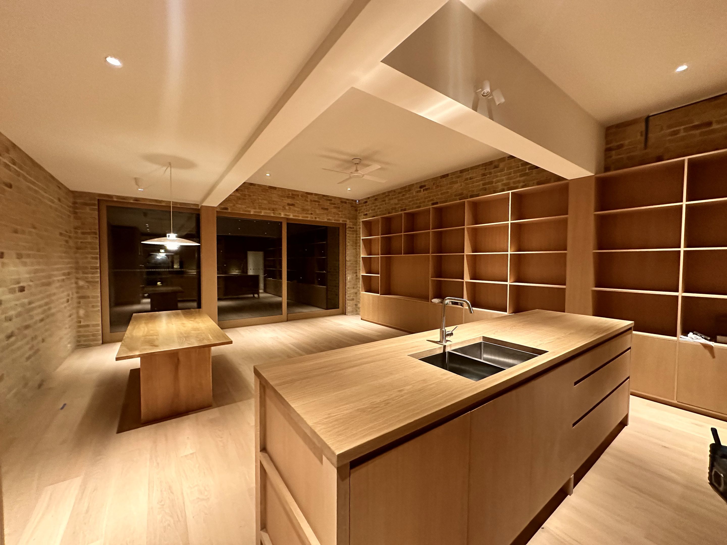 Kitchen island with integrated sink beside built-in timber shelving