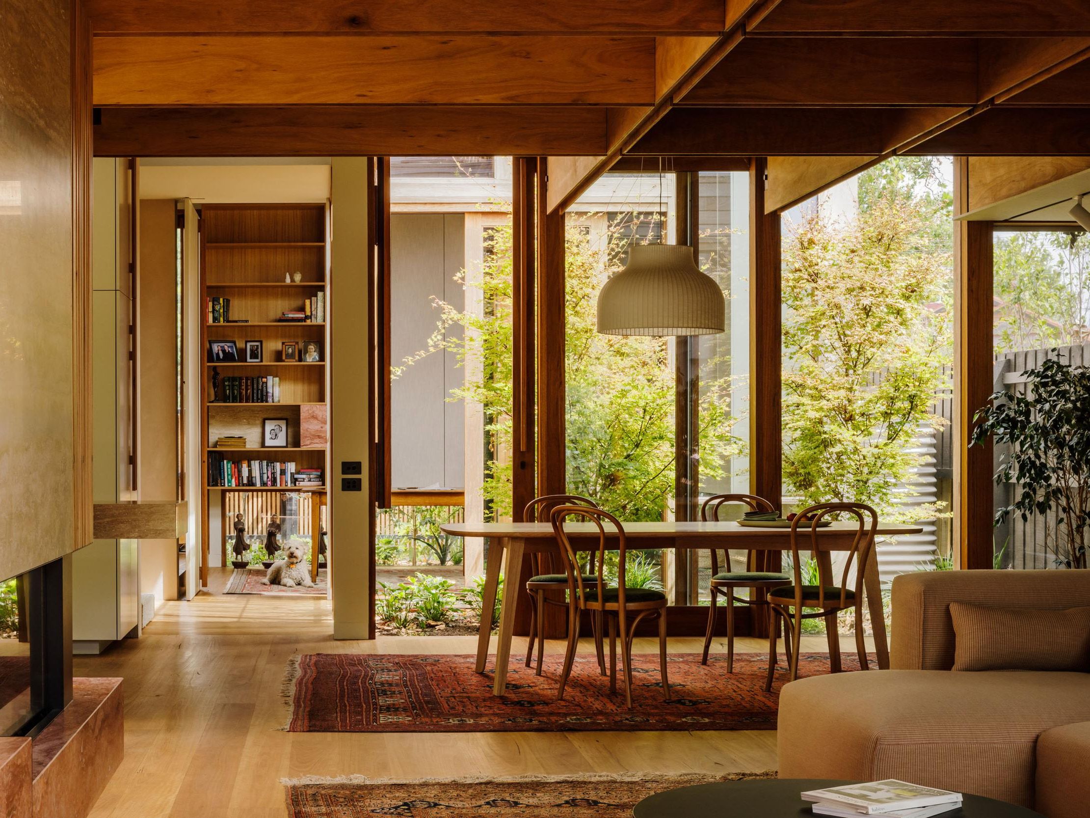 Dining table under a pendant light beside a bookshelf hallway