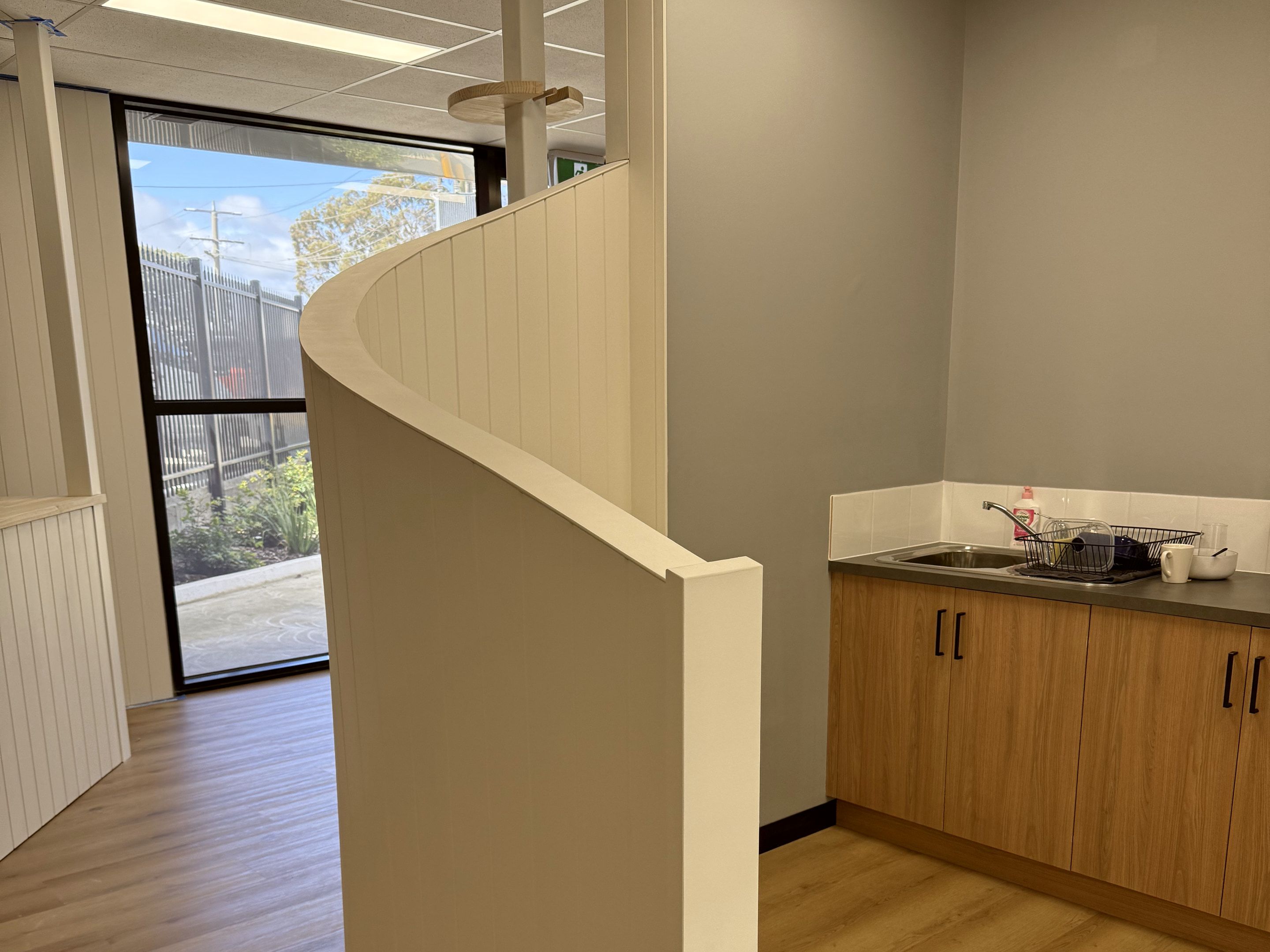 Curved partition wall beside a small kitchenette sink