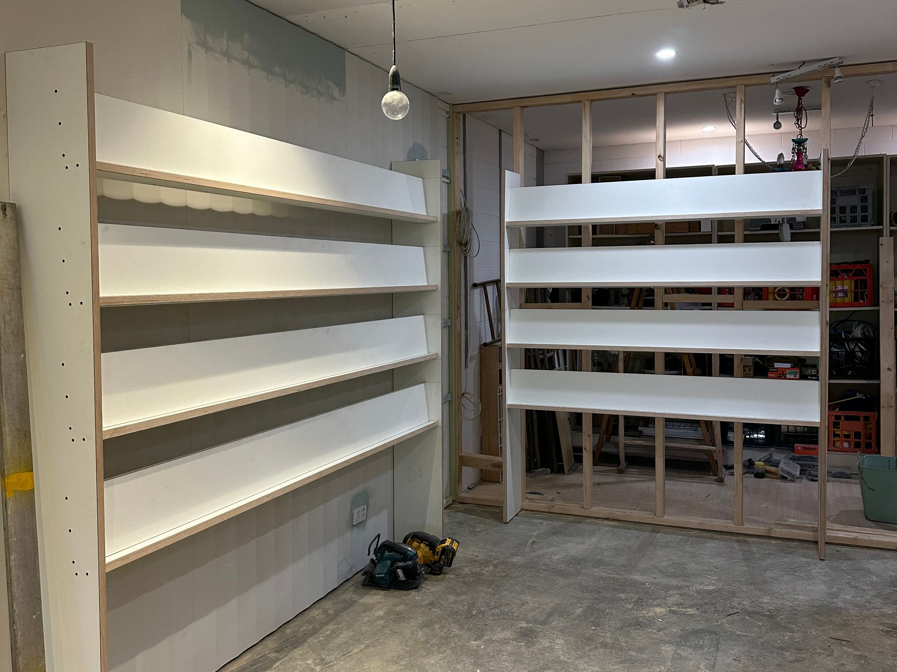 Half-built white shelving units in a partly fitted-out shop