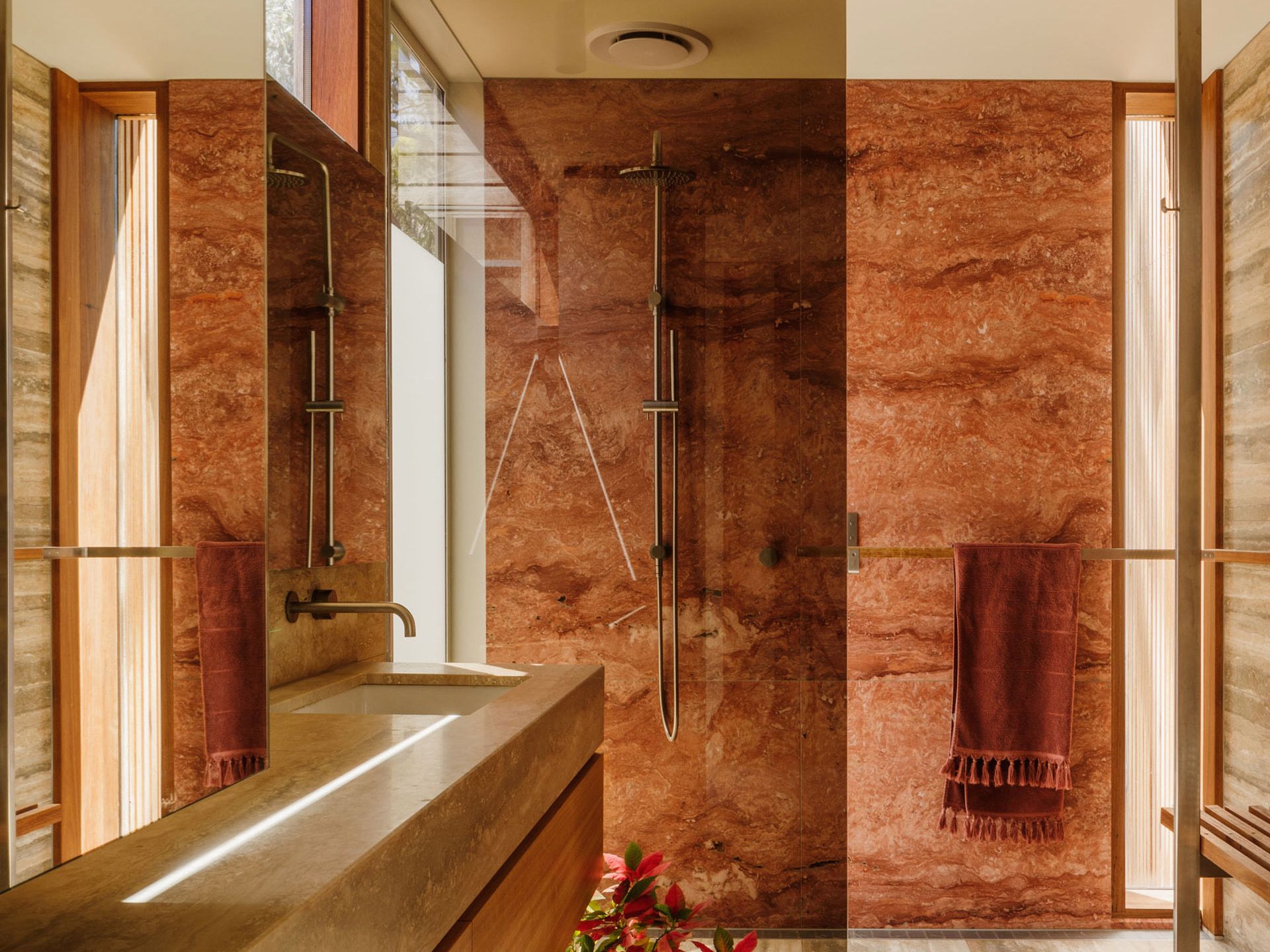 Bathroom with veined stone walls, twin shower heads and a towel rail