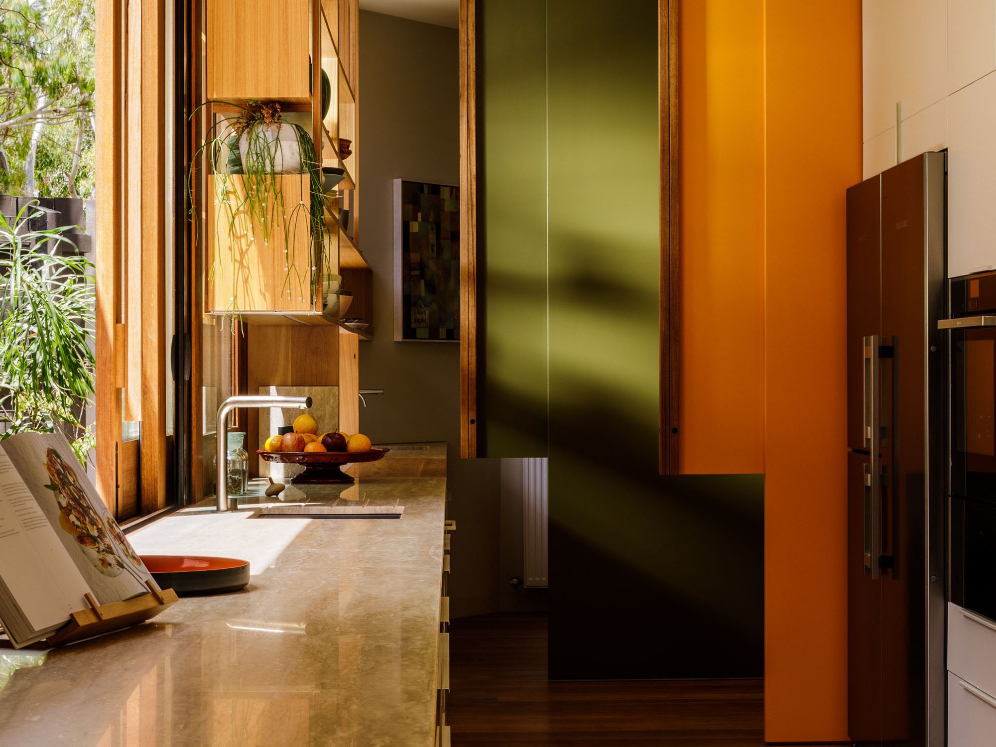 Kitchen sink and cabinetry beside a sunlit courtyard doorway