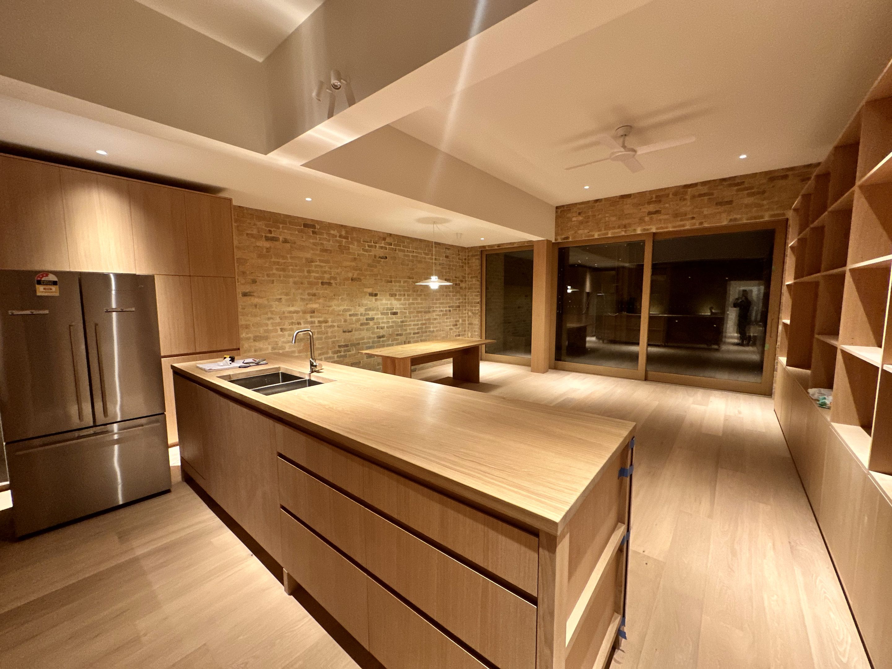Kitchen island and dining area beside an exposed brick wall, at night